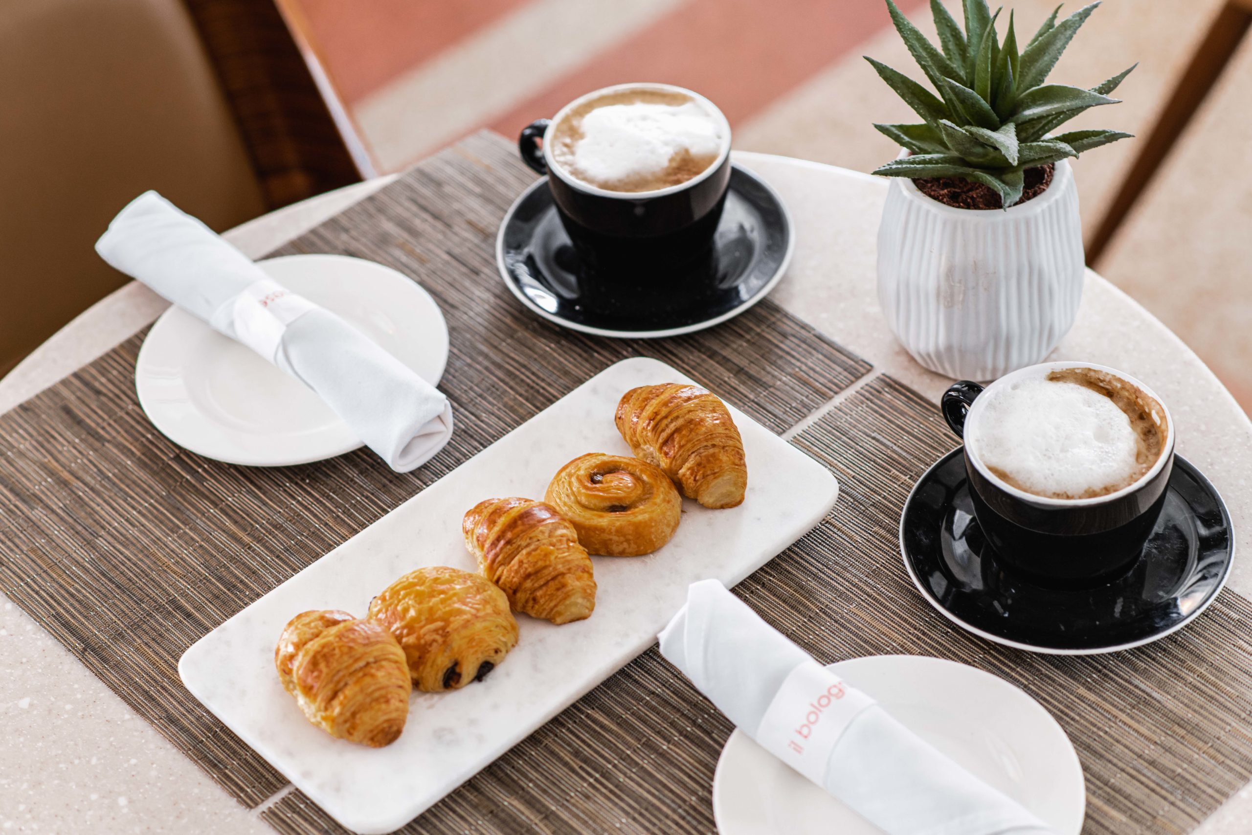 Cappuccinos and fresh pastries on a marble tray at a hotel cafe table