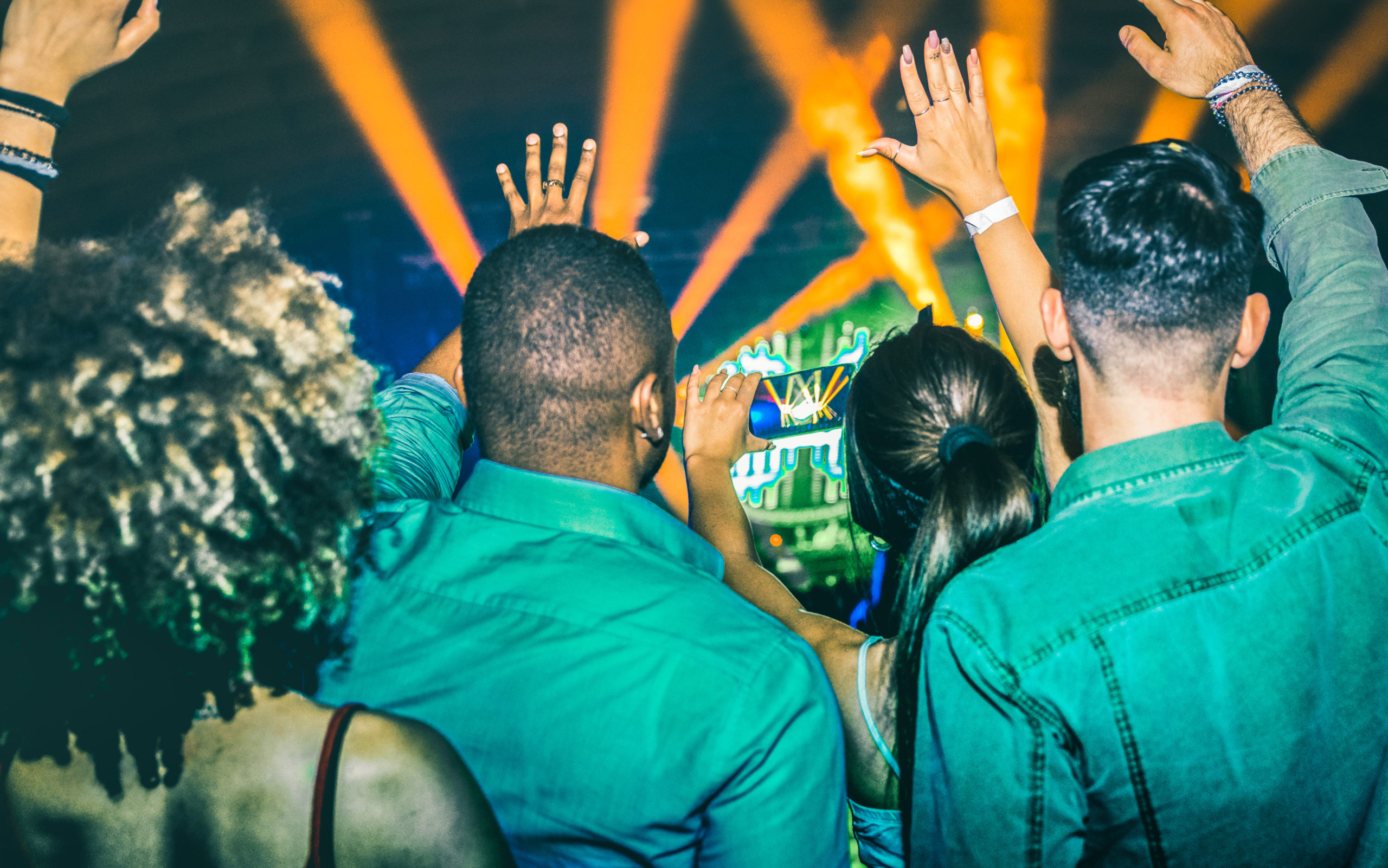 Friends cheering at a live music show with orange stage lights